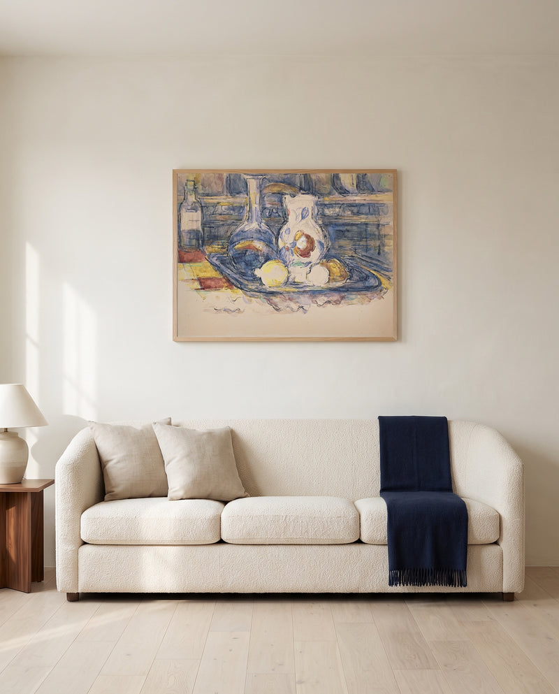 Bottle, Carafe and Jug by Paul Cézanne framed in natural oak above a cream sofa in a warm living room