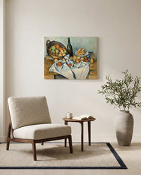 The Basket of Apples by Paul Cézanne as a stretched canvas above a linen lounge chair in a reading corner