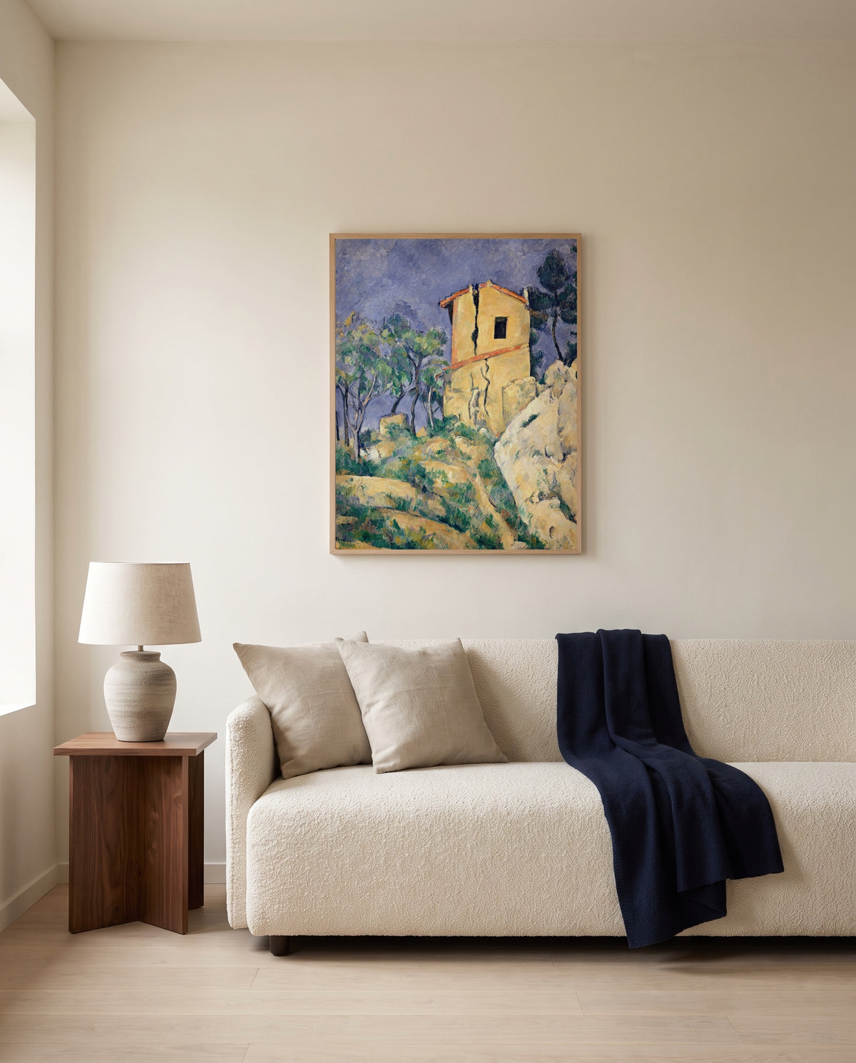 House with Cracked Walls by Paul Cézanne framed in natural oak above a cream sofa in a warm living room