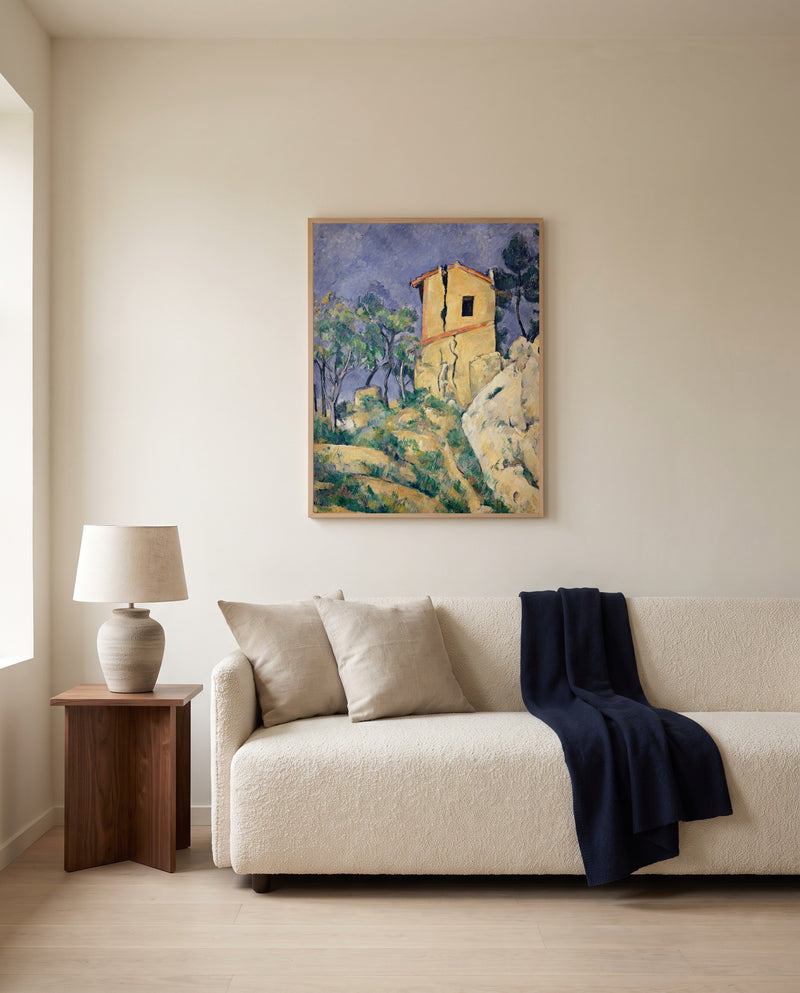 House with Cracked Walls by Paul Cézanne framed in natural oak above a cream sofa in a warm living room