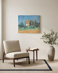 The Pigeon Tower at Bellevue by Paul Cézanne as a stretched canvas above a linen lounge chair in a reading corner