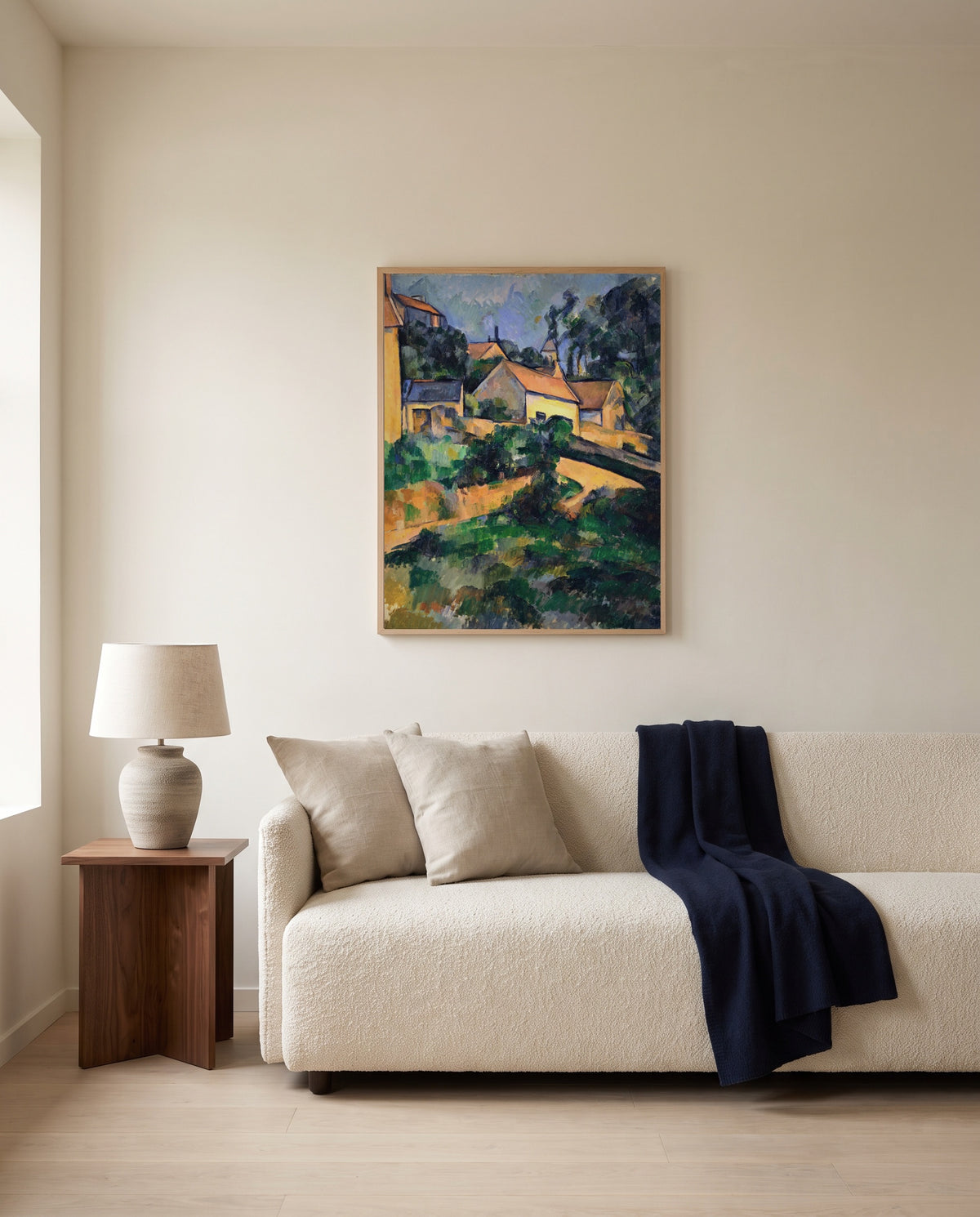 Road at Montgeroult by Paul Cézanne framed in natural oak above a cream sofa in a warm living room