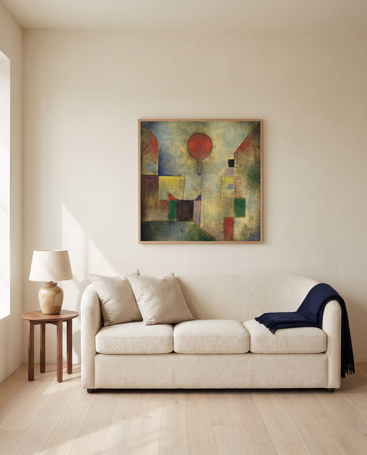Red Balloon by Paul Klee framed in natural oak above a cream sofa in a warm living room