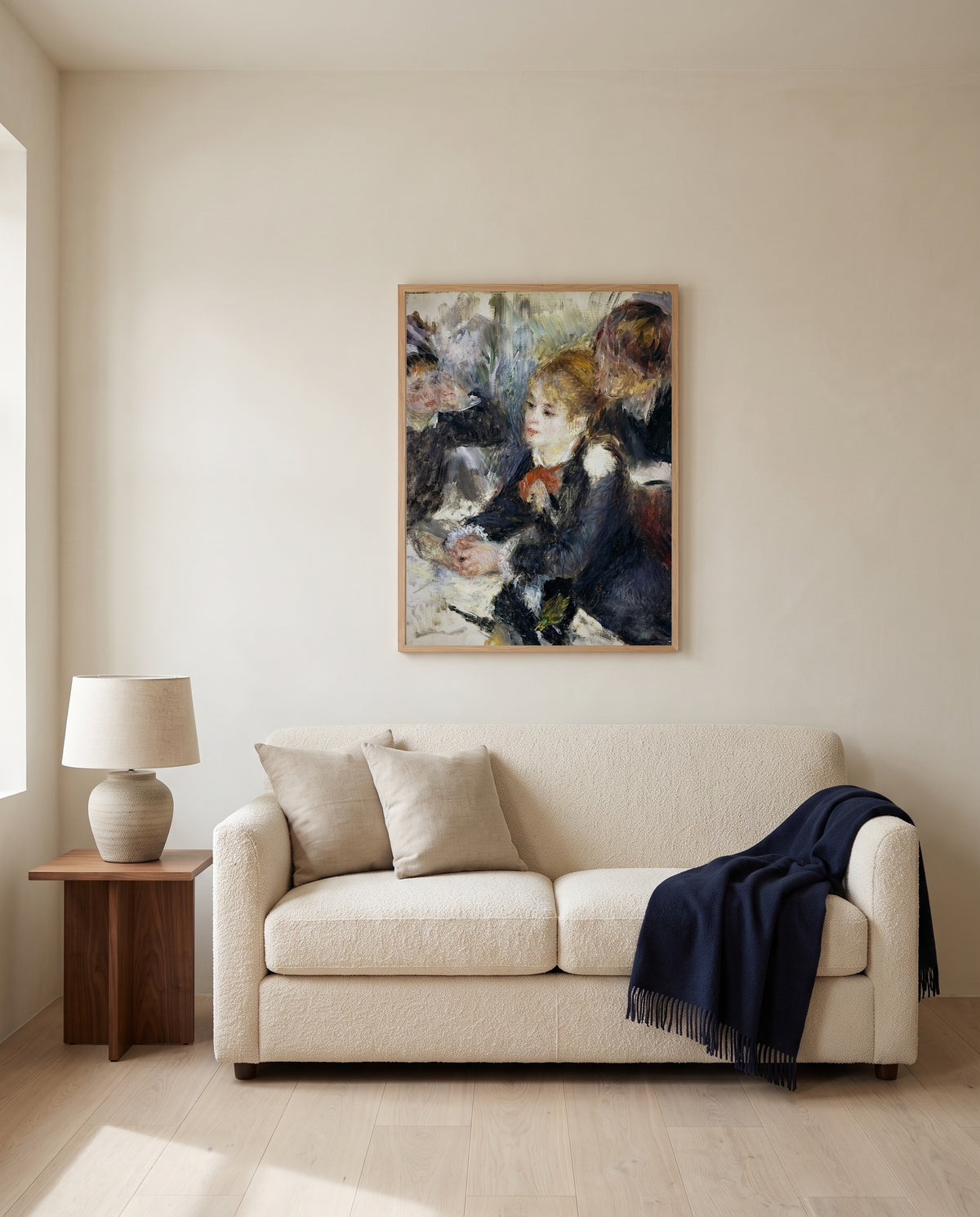 At the Milliner’s by Pierre-Auguste Renoir framed in natural oak above a cream sofa in a warm living room