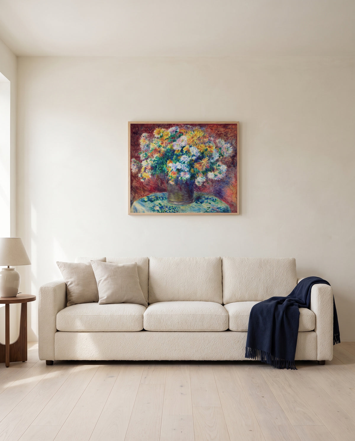 Chrysanthemums by Pierre-Auguste Renoir framed in natural oak above a cream sofa in a warm living room