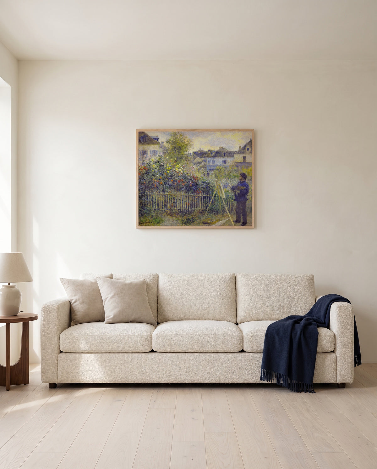 Monet in His Garden by Pierre-Auguste Renoir framed in natural oak above a cream sofa in a warm living room