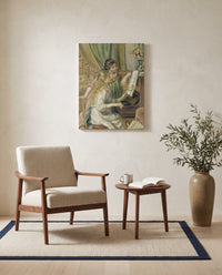Young Girls at the Piano by Pierre-Auguste Renoir as a stretched canvas above a linen lounge chair in a reading corner