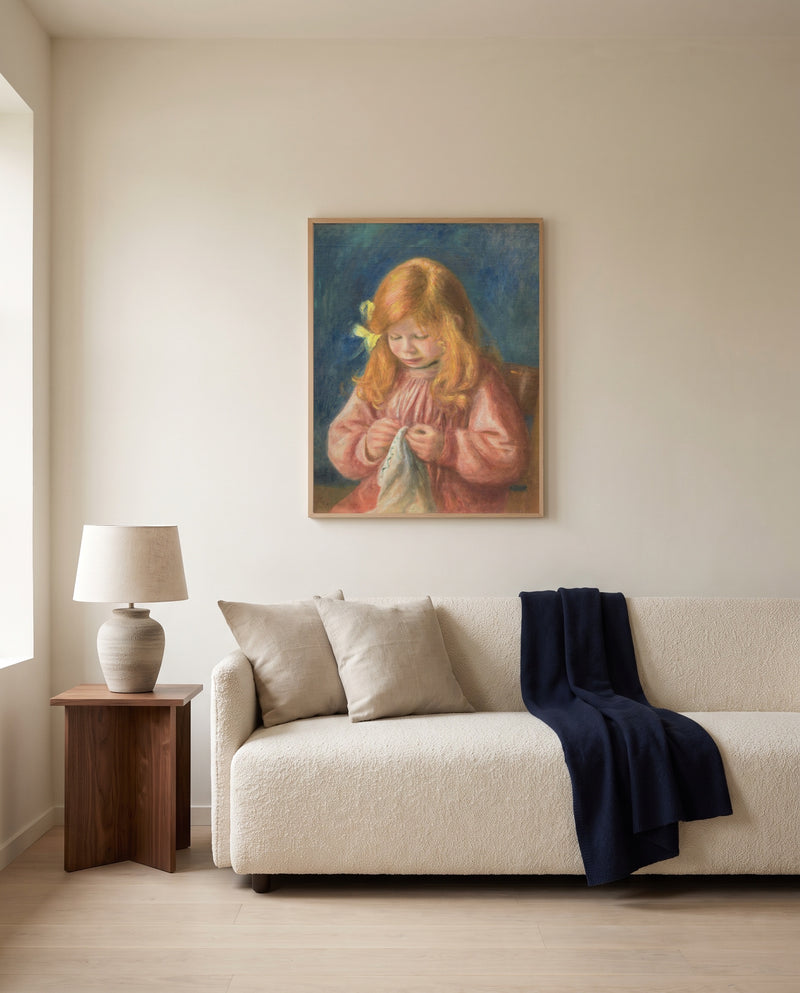 Jean Renoir Sewing by Pierre-Auguste Renoir framed in natural oak above a cream sofa in a warm living room