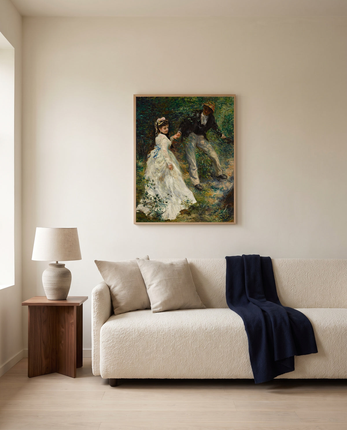 La Promenade by Pierre-Auguste Renoir framed in natural oak above a cream sofa in a warm living room