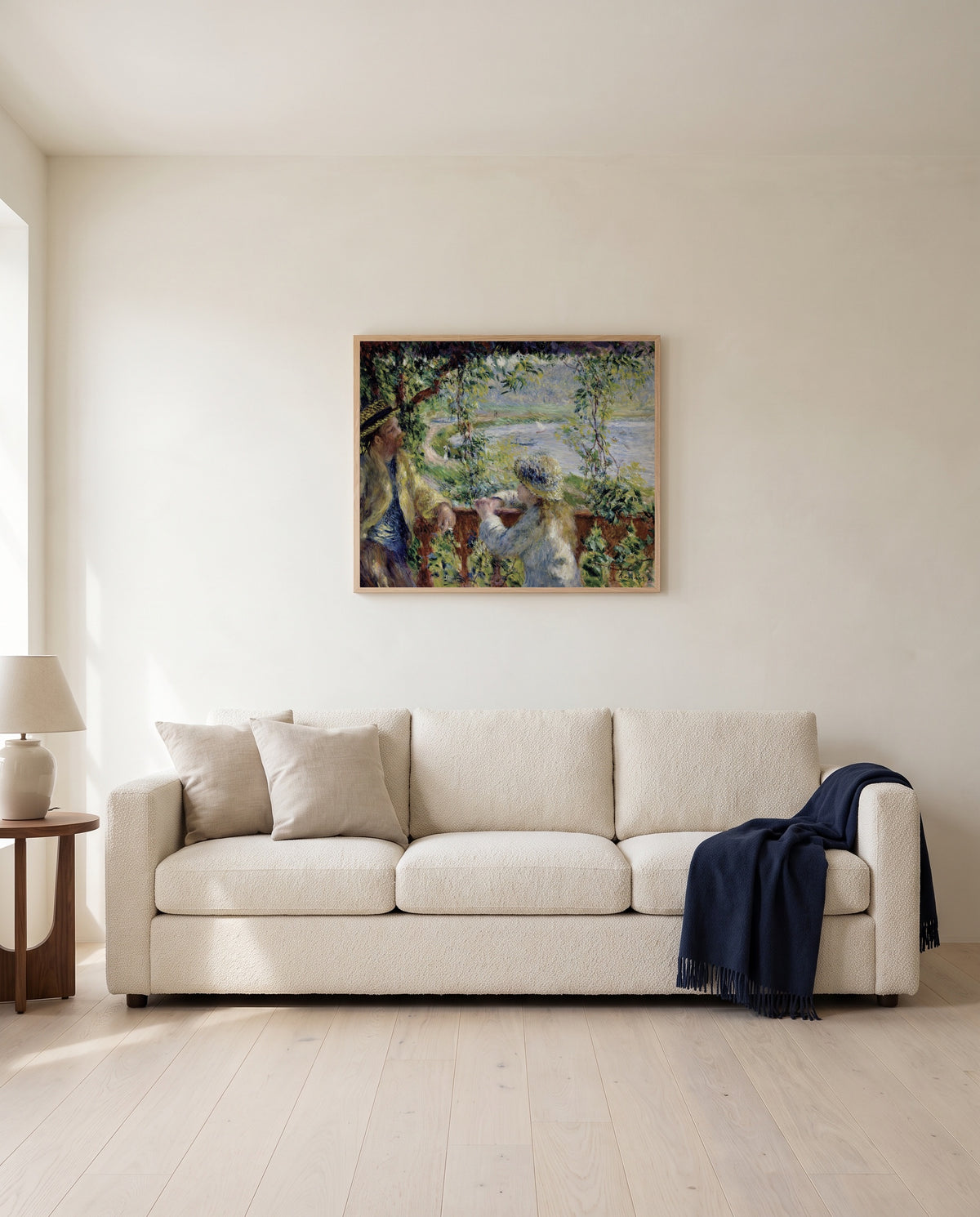 Near the Lake by Pierre-Auguste Renoir framed in natural oak above a cream sofa in a warm living room