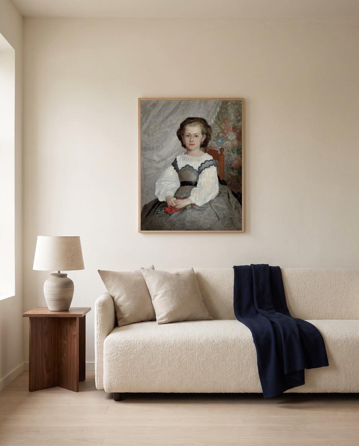 Romaine Lacaux by Pierre-Auguste Renoir framed in natural oak above a cream sofa in a warm living room