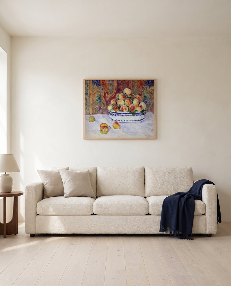 Still Life with Peaches by Pierre-Auguste Renoir framed in natural oak above a cream sofa in a warm living room