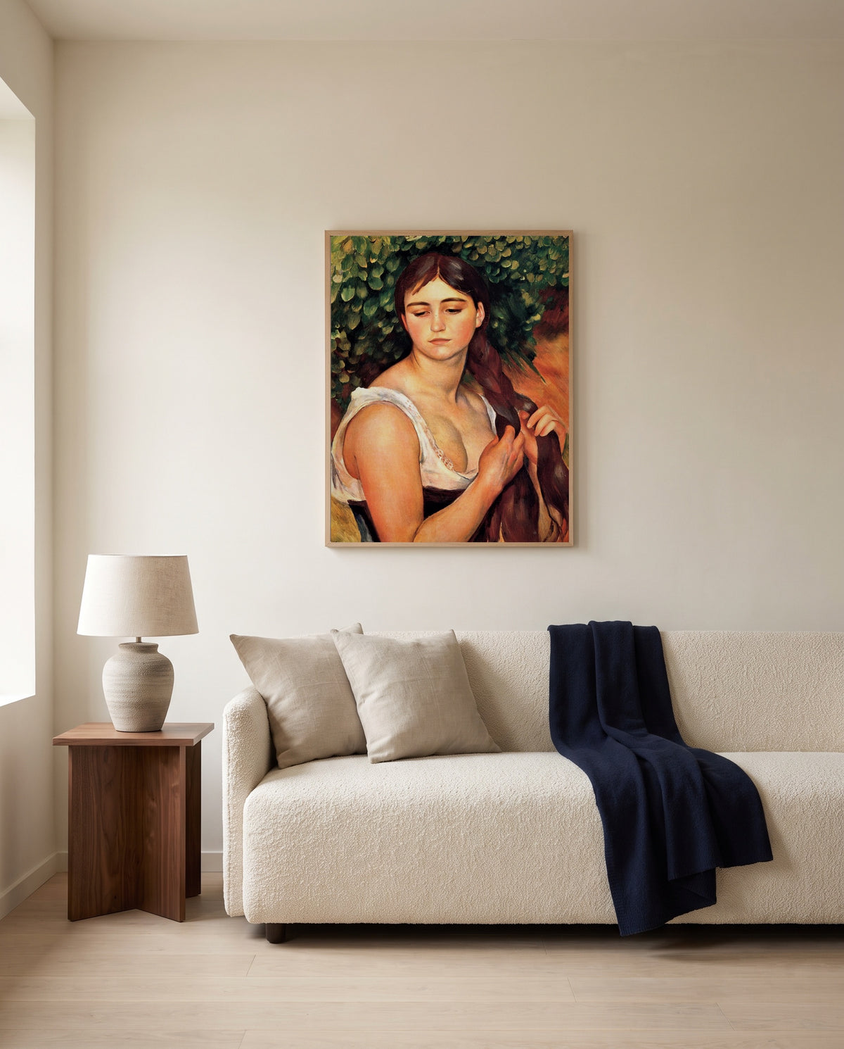 The Braid by Pierre-Auguste Renoir framed in natural oak above a cream sofa in a warm living room
