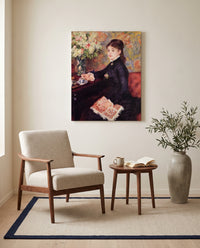 The Cup of Chocolate by Pierre-Auguste Renoir as a stretched canvas above a linen lounge chair in a reading corner