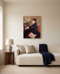 The Cup of Chocolate by Pierre-Auguste Renoir framed in natural oak above a cream sofa in a warm living room