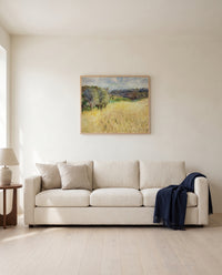 Wheatfield by Pierre-Auguste Renoir framed in natural oak above a cream sofa in a warm living room