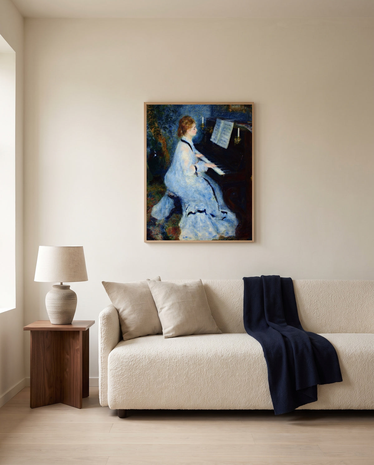 Woman at the Piano by Pierre-Auguste Renoir framed in natural oak above a cream sofa in a warm living room