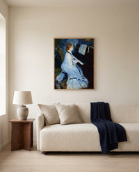 Woman at the Piano by Pierre-Auguste Renoir framed in natural oak above a cream sofa in a warm living room