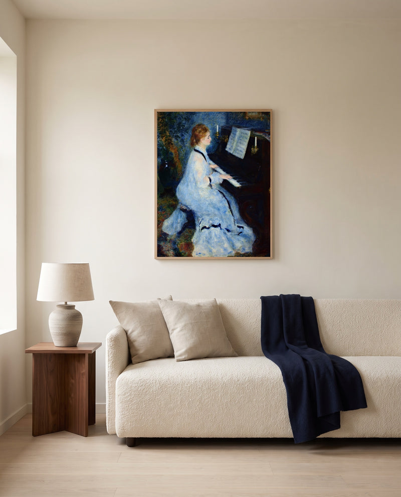 Woman at the Piano by Pierre-Auguste Renoir framed in natural oak above a cream sofa in a warm living room