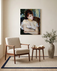 Woman in an Armchair by Pierre-Auguste Renoir as a stretched canvas above a linen lounge chair in a reading corner