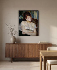 Woman in an Armchair by Pierre-Auguste Renoir in a black frame above a walnut sideboard in a dining room