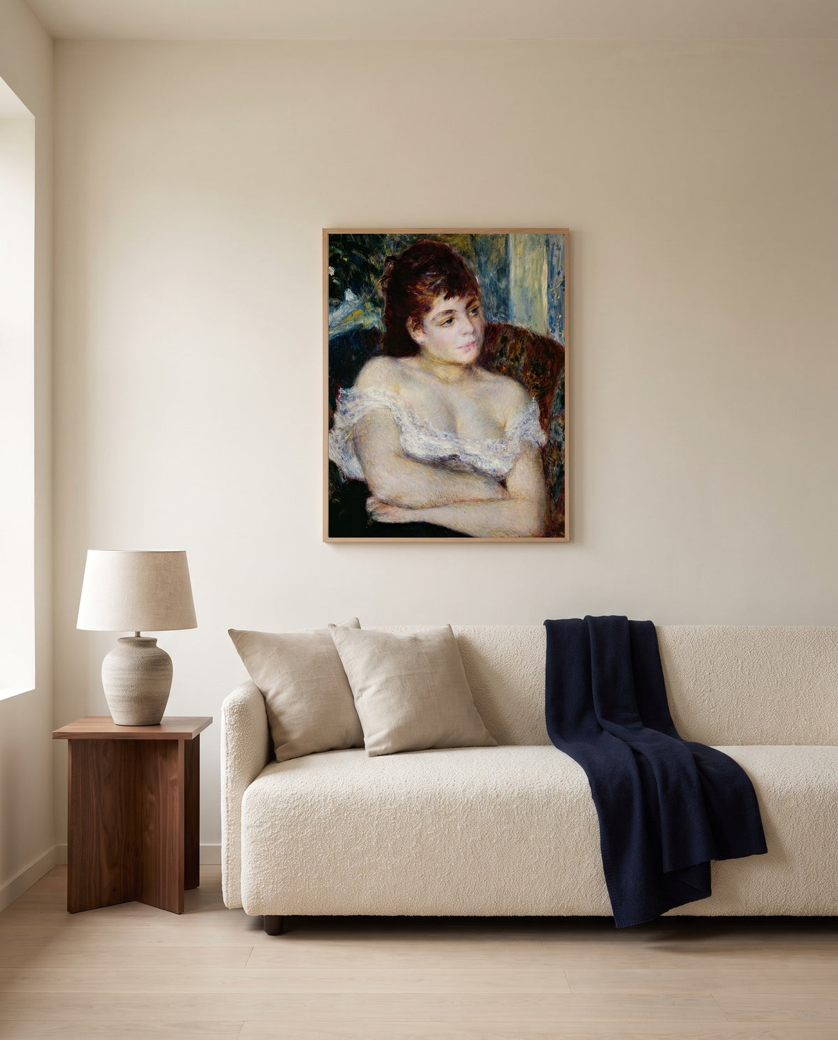 Woman in an Armchair by Pierre-Auguste Renoir framed in natural oak above a cream sofa in a warm living room