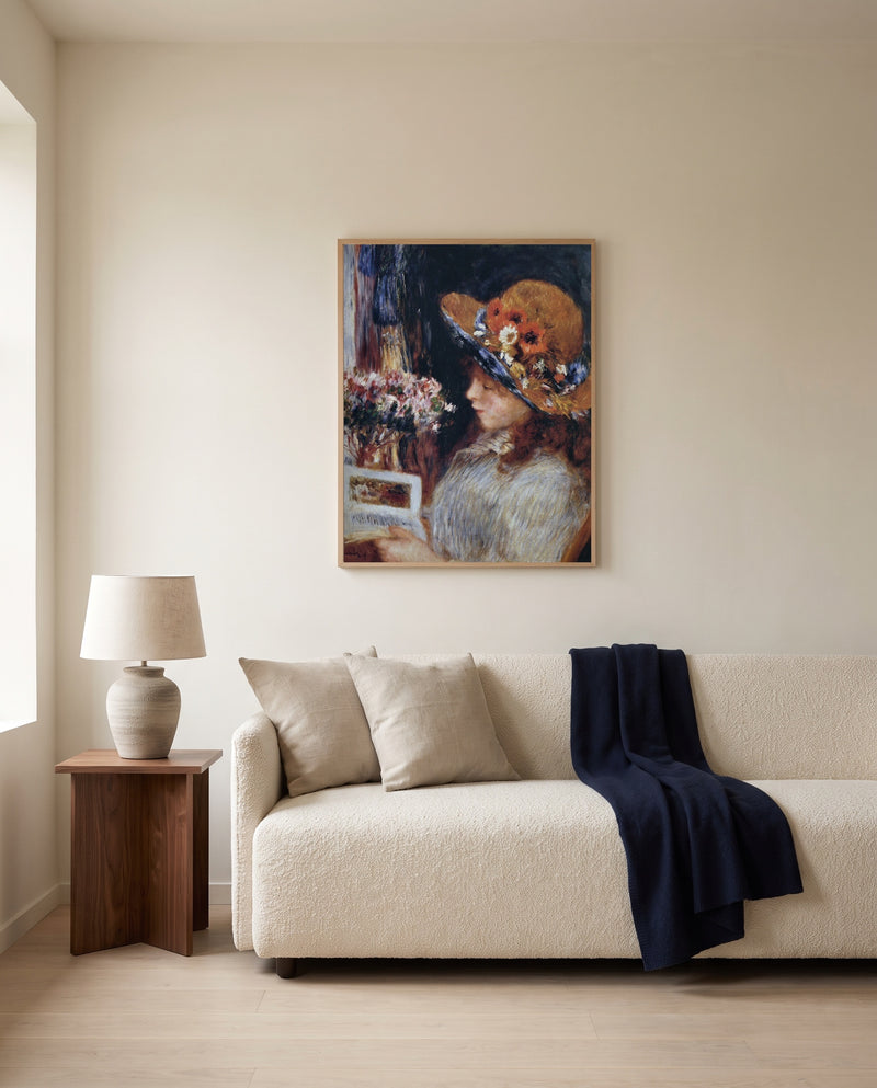 Reading Girl by Pierre-Auguste Renoir framed in natural oak above a cream sofa in a warm living room