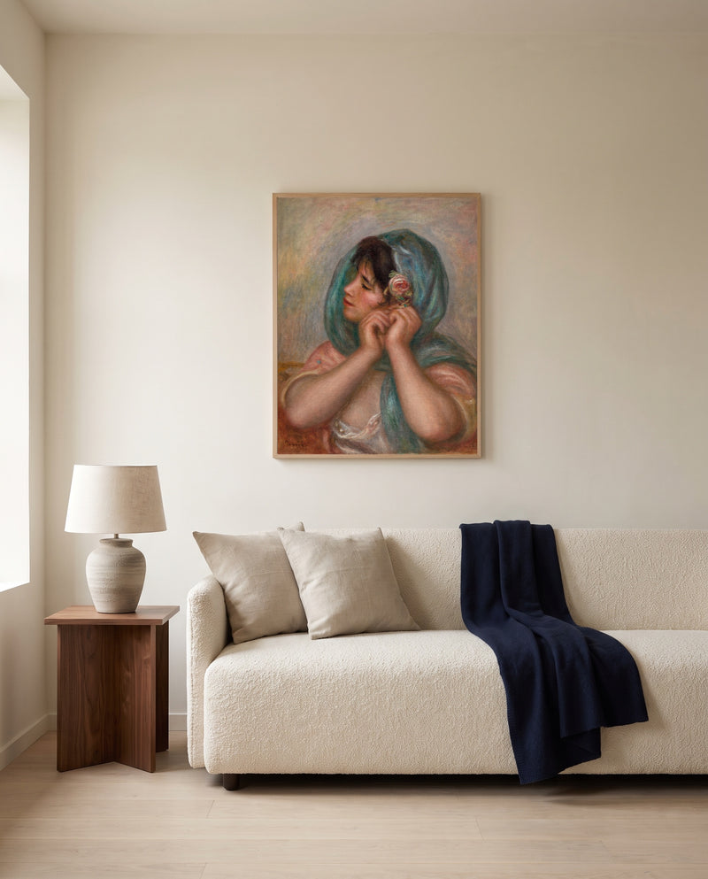 Young Woman Arranging Her Earring by Pierre-Auguste Renoir framed in natural oak above a cream sofa in a warm living room