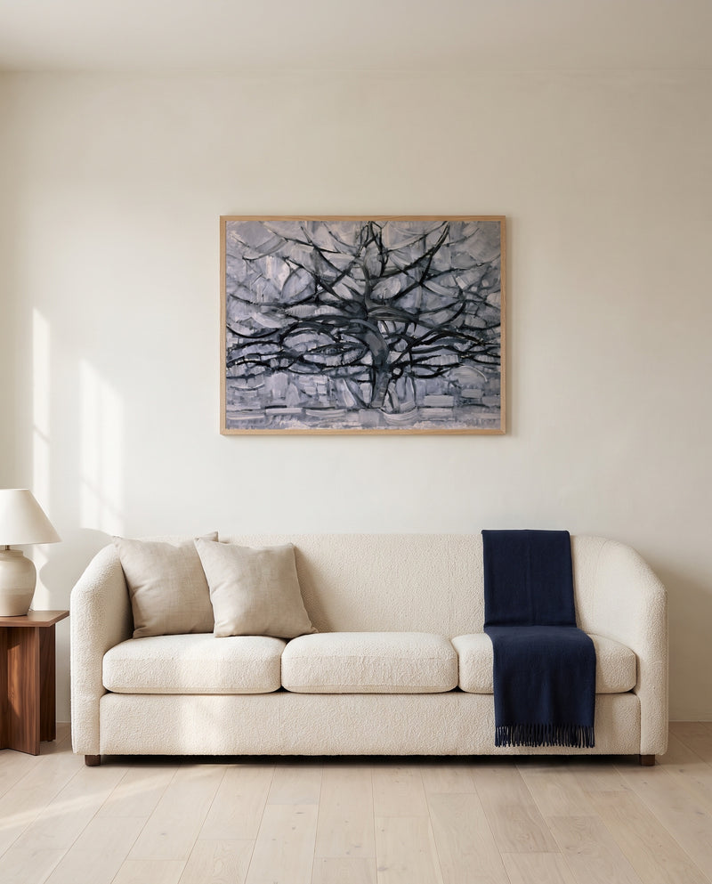 Gray Tree by Piet Mondrian framed in natural oak above a cream sofa in a warm living room