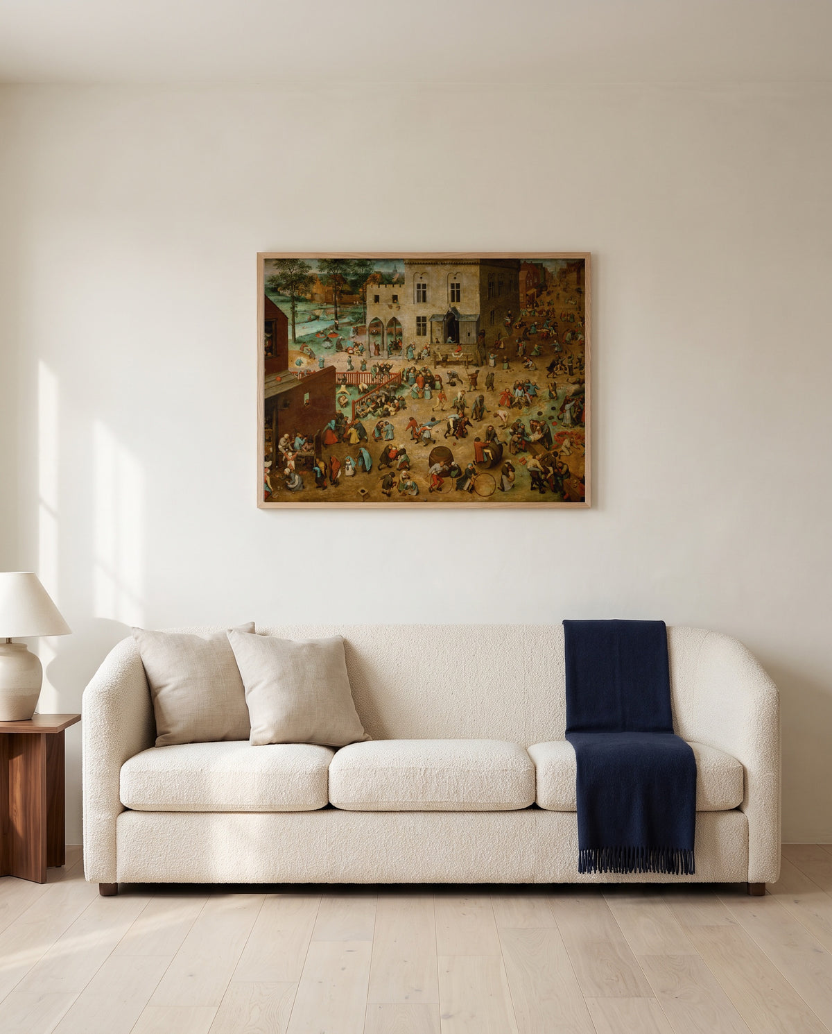 Children’s Games by Pieter Bruegel the Elder framed in natural oak above a cream sofa in a warm living room