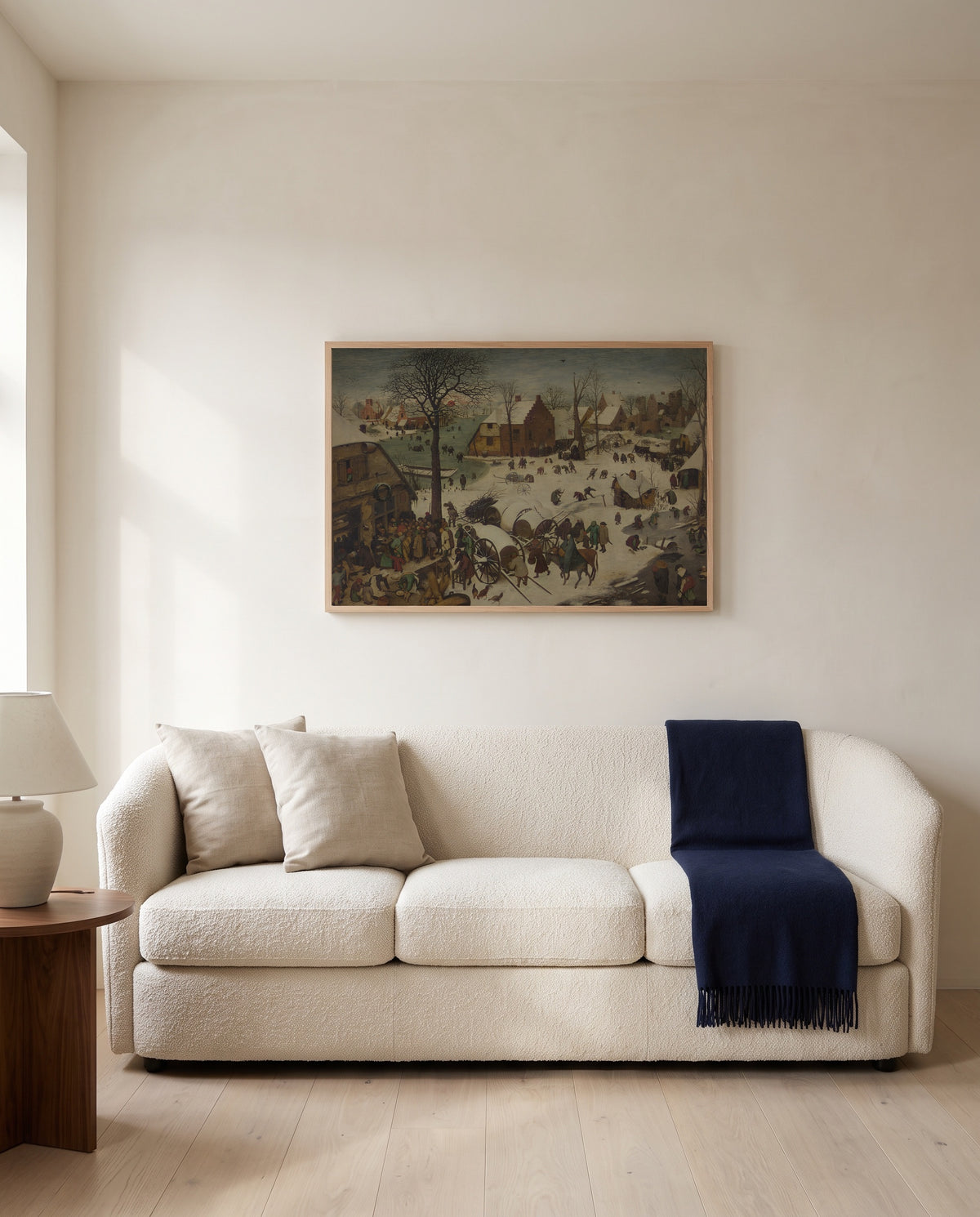 The Census at Bethlehem by Pieter Bruegel the Elder framed in natural oak above a cream sofa in a warm living room