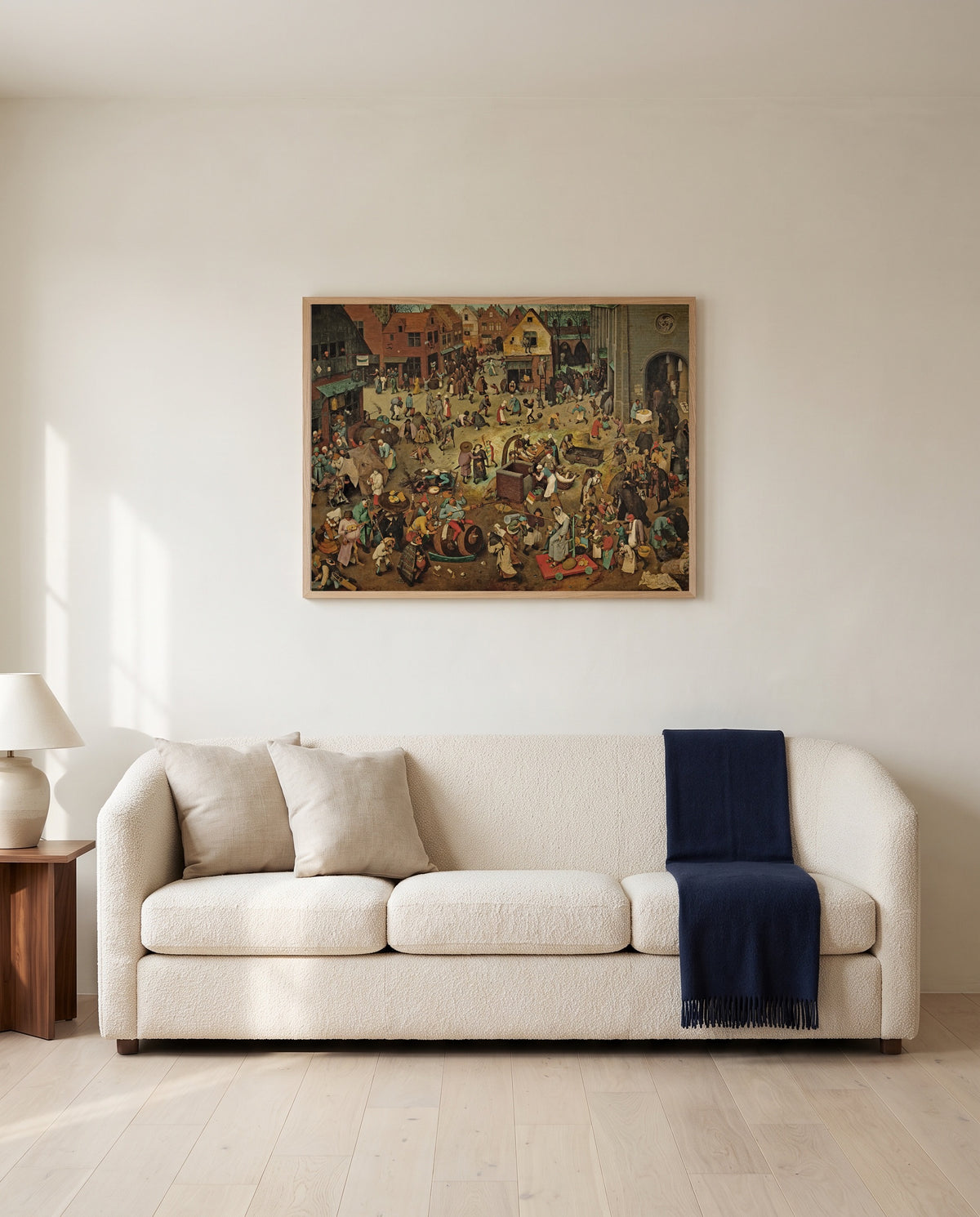 Carnival and Lent by Pieter Bruegel the Elder framed in natural oak above a cream sofa in a warm living room