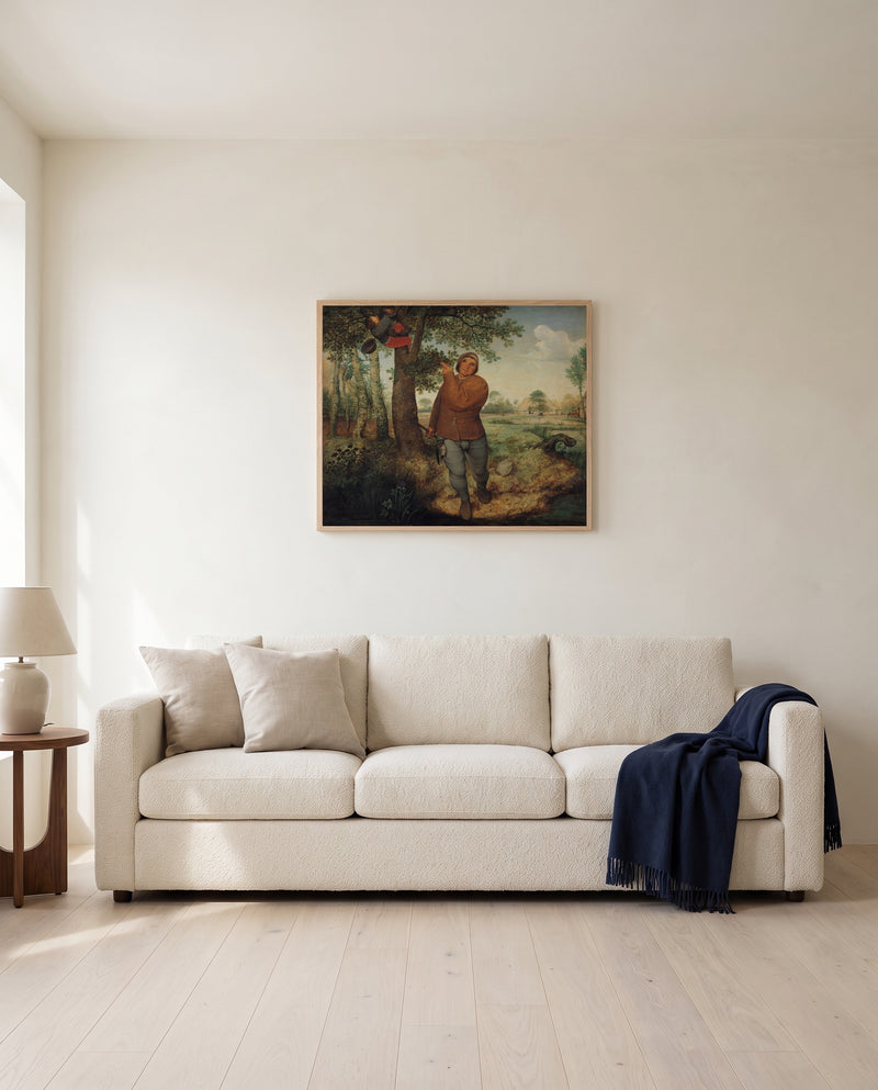 The Nest Robber by Pieter Bruegel the Elder framed in natural oak above a cream sofa in a warm living room