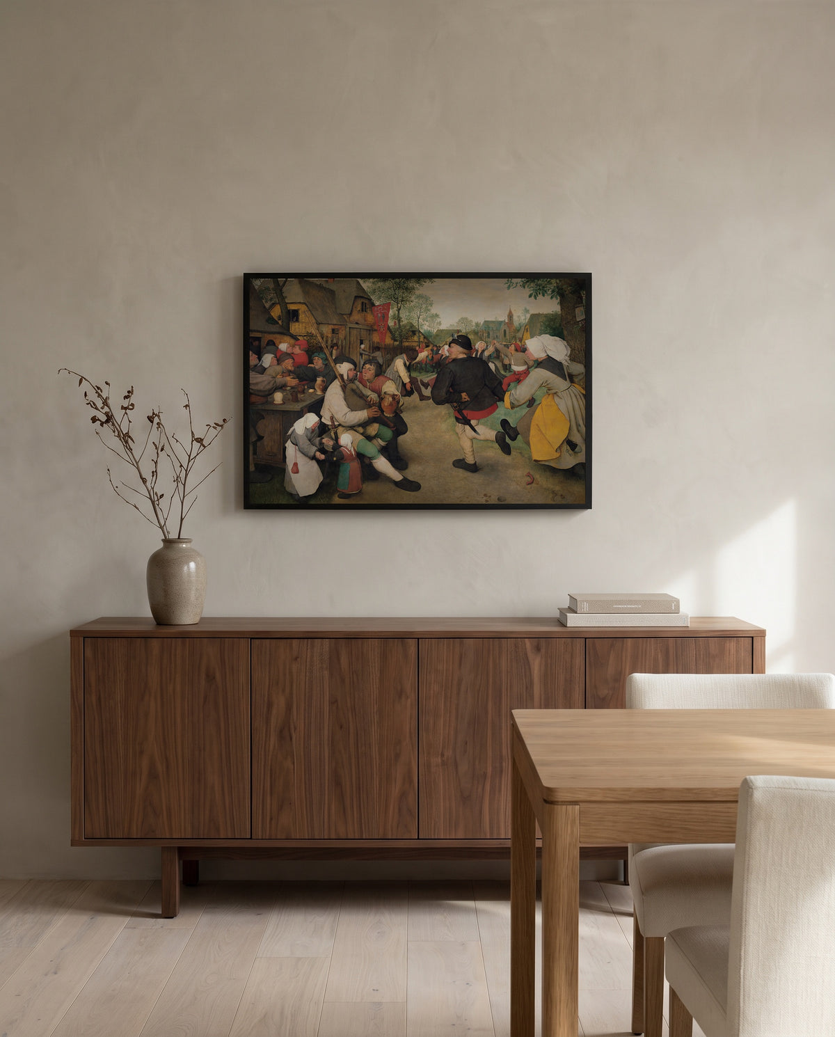 The Peasant Dance by Pieter Bruegel the Elder in a black frame above a walnut sideboard in a dining room
