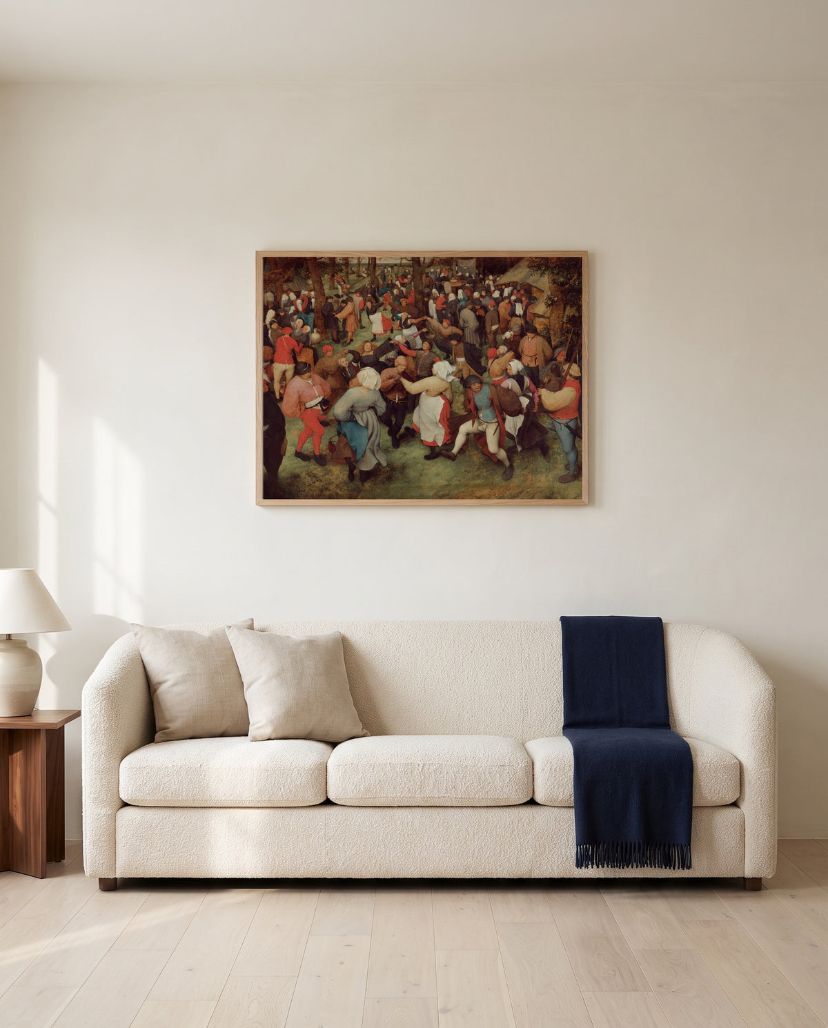 The Wedding Dance by Pieter Bruegel the Elder framed in natural oak above a cream sofa in a warm living room