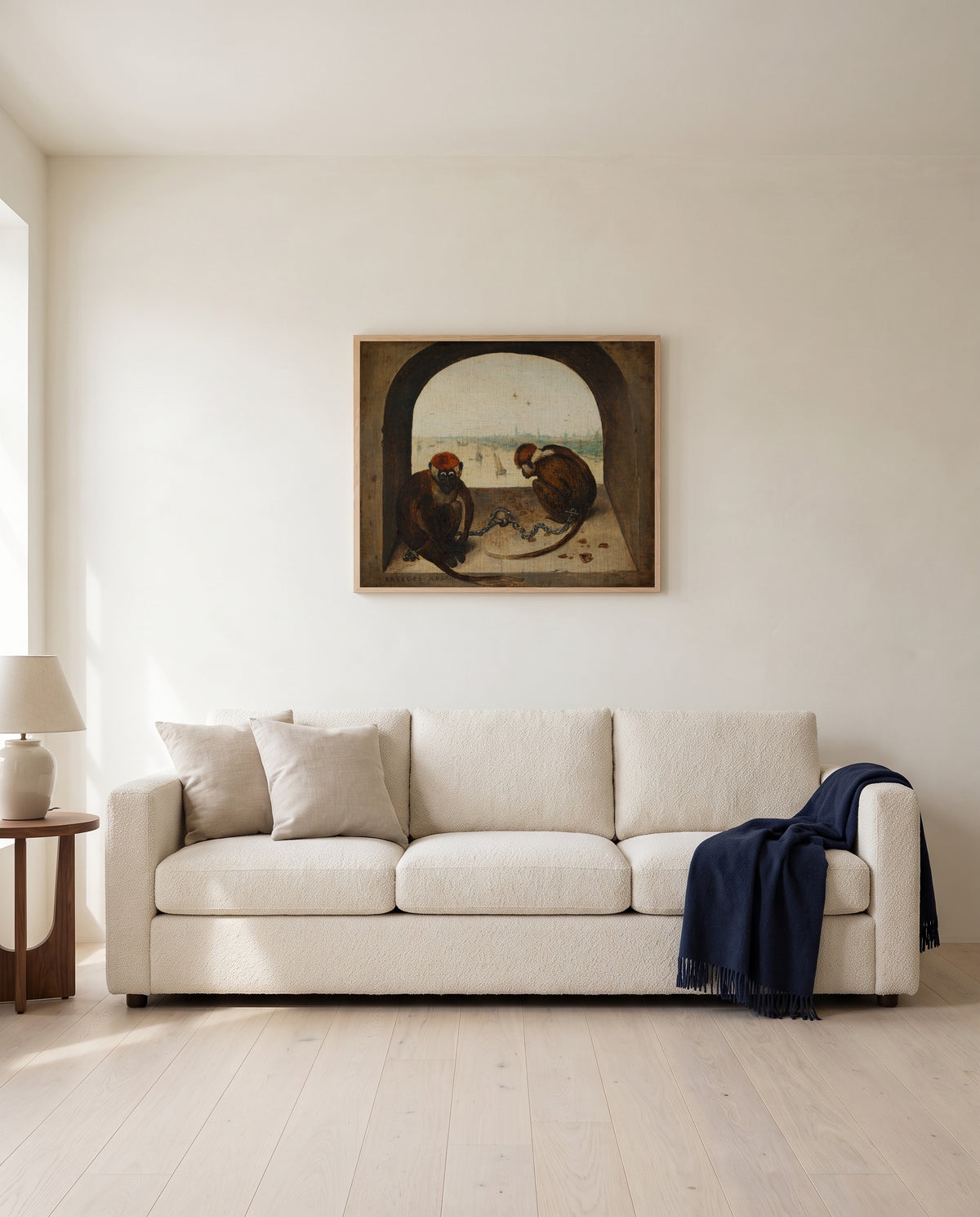 Two Chained Monkeys by Pieter Bruegel the Elder framed in natural oak above a cream sofa in a warm living room