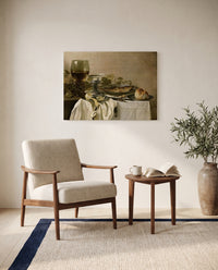 Still Life with a Fish by Pieter Claesz as a stretched canvas above a linen lounge chair in a reading corner