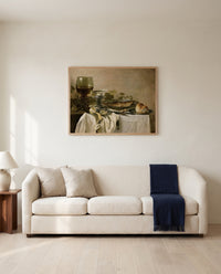 Still Life with a Fish by Pieter Claesz framed in natural oak above a cream sofa in a warm living room