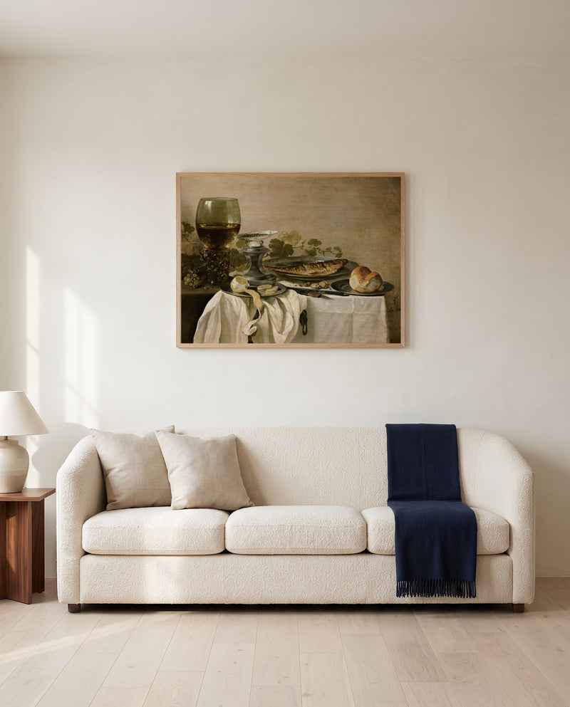 Still Life with a Fish by Pieter Claesz framed in natural oak above a cream sofa in a warm living room