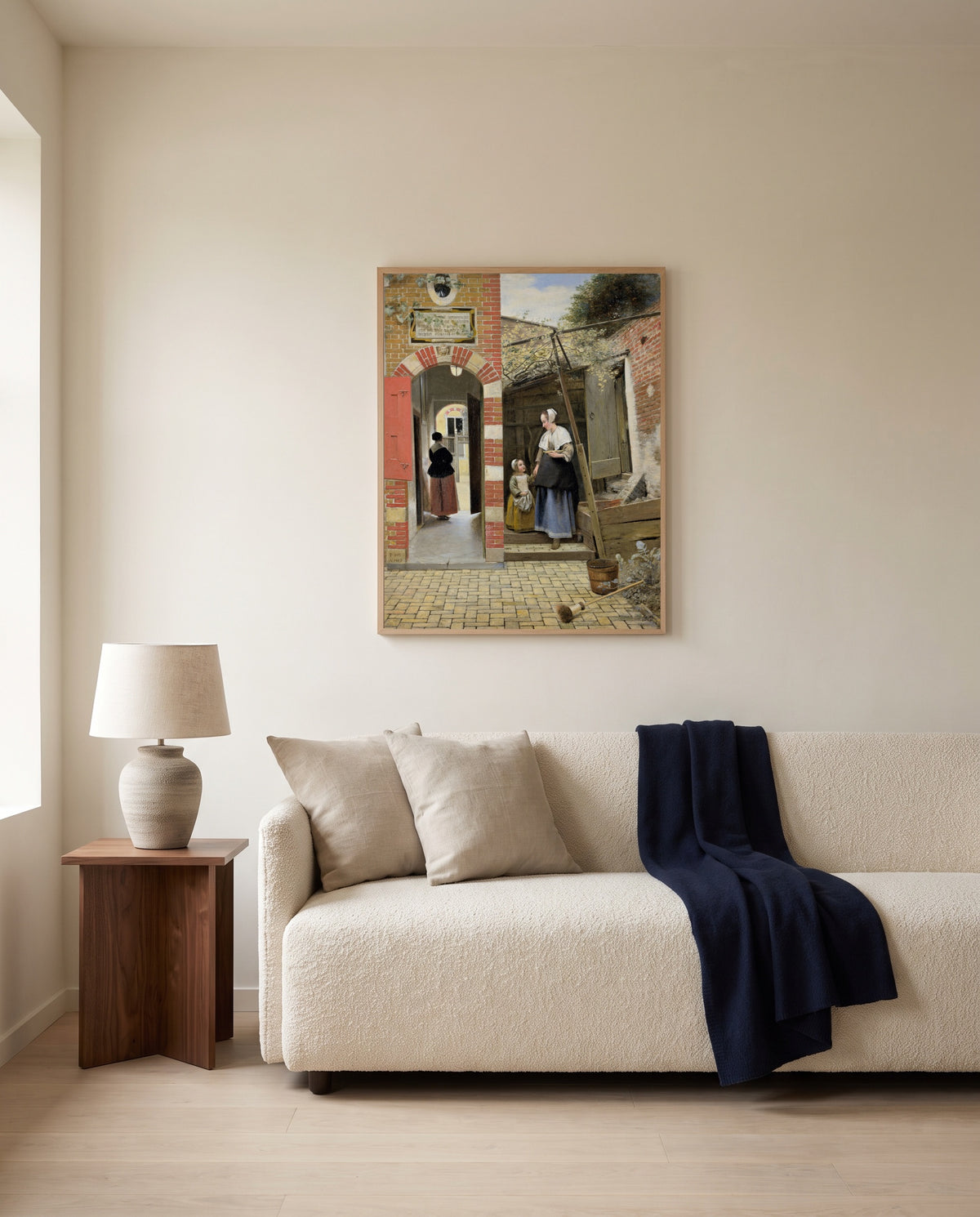 Courtyard in Delft by Pieter de Hooch framed in natural oak above a cream sofa in a warm living room