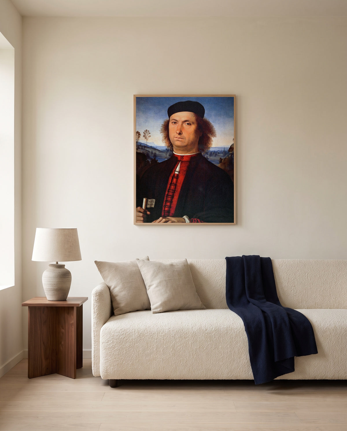 Francesco delle Opere by Pietro Perugino framed in natural oak above a cream sofa in a warm living room