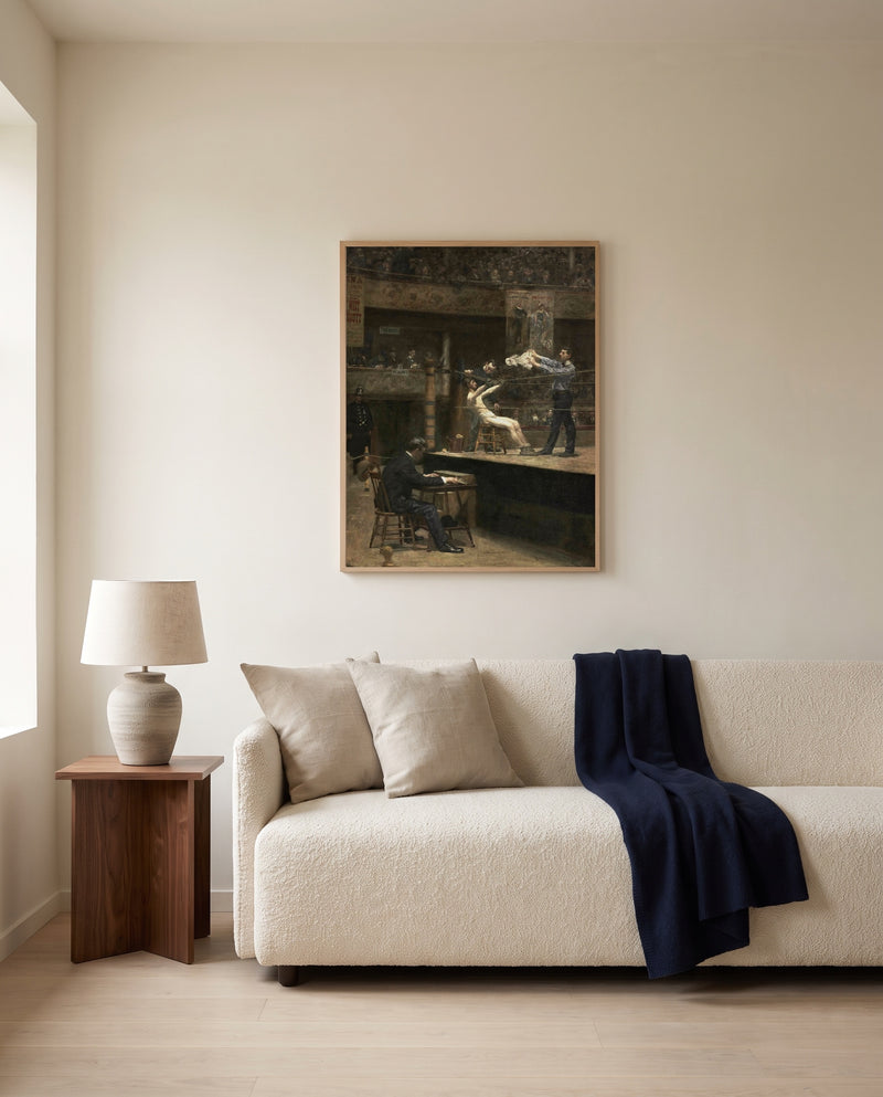 Between Rounds by Thomas Eakins framed in natural oak above a cream sofa in a warm living room