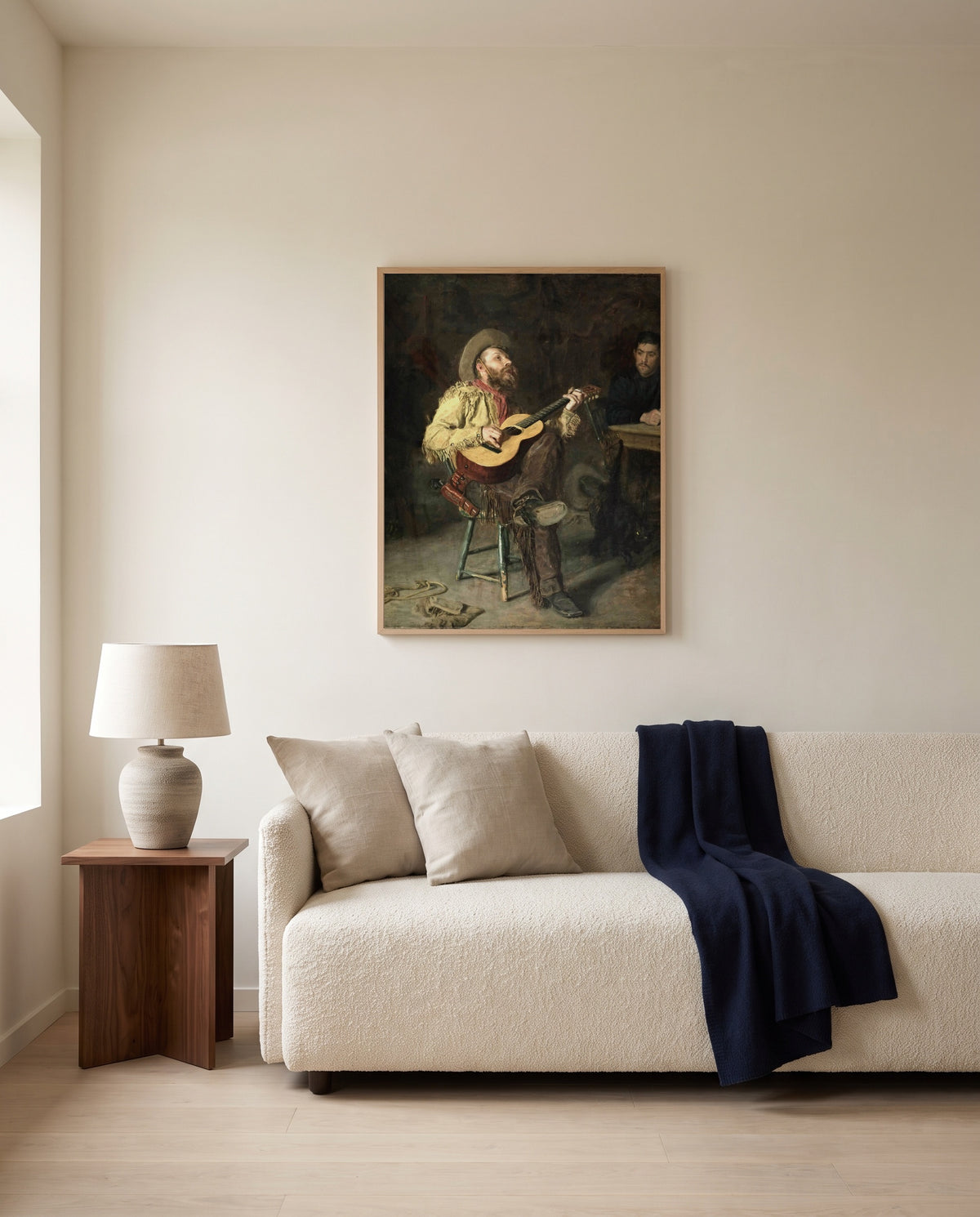 Home Ranch by Thomas Eakins framed in natural oak above a cream sofa in a warm living room