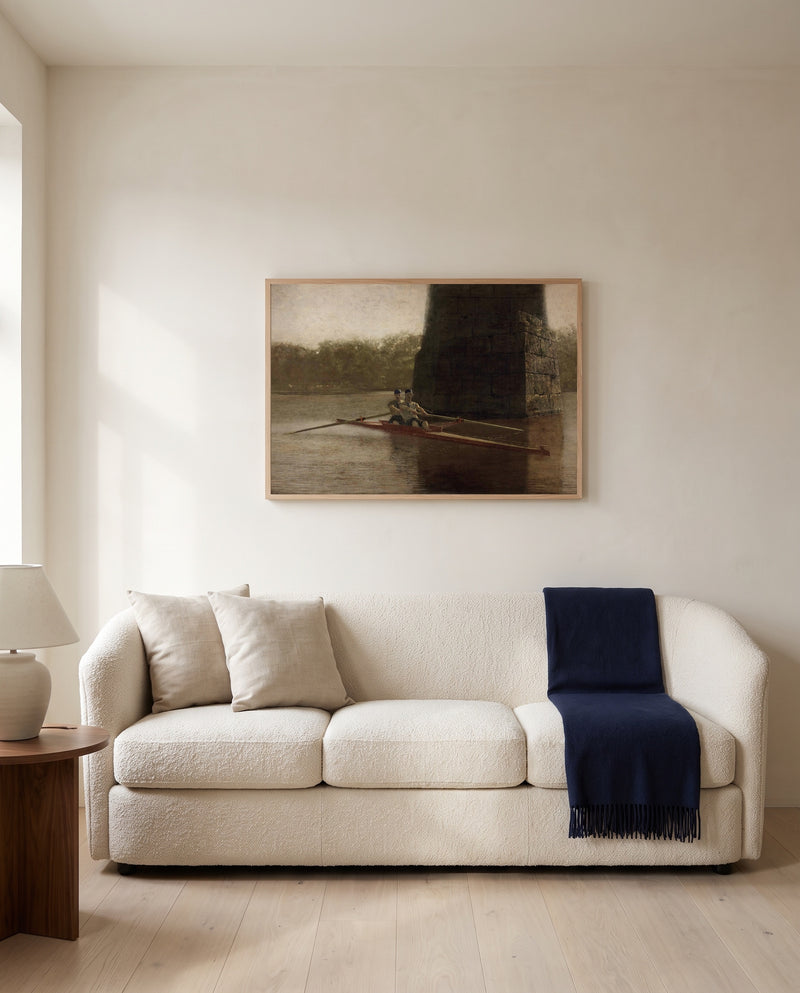 The Pair-Oared Shell by Thomas Eakins framed in natural oak above a cream sofa in a warm living room