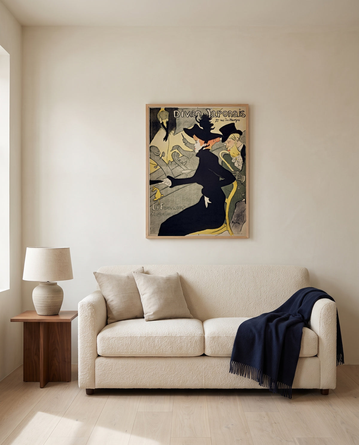 Divan Japonais by Henri de Toulouse-Lautrec framed in natural oak above a cream sofa in a warm living room
