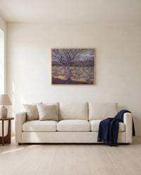 Apricot Trees in Blossom by Vincent van Gogh framed in natural oak above a cream sofa in a warm living room