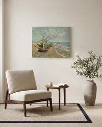 Fishing Boats on the Beach by Vincent van Gogh as a stretched canvas above a linen lounge chair in a reading corner