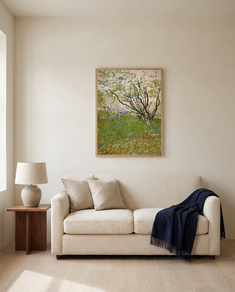 The Flowering Orchard by Vincent van Gogh framed in natural oak above a cream sofa in a warm living room