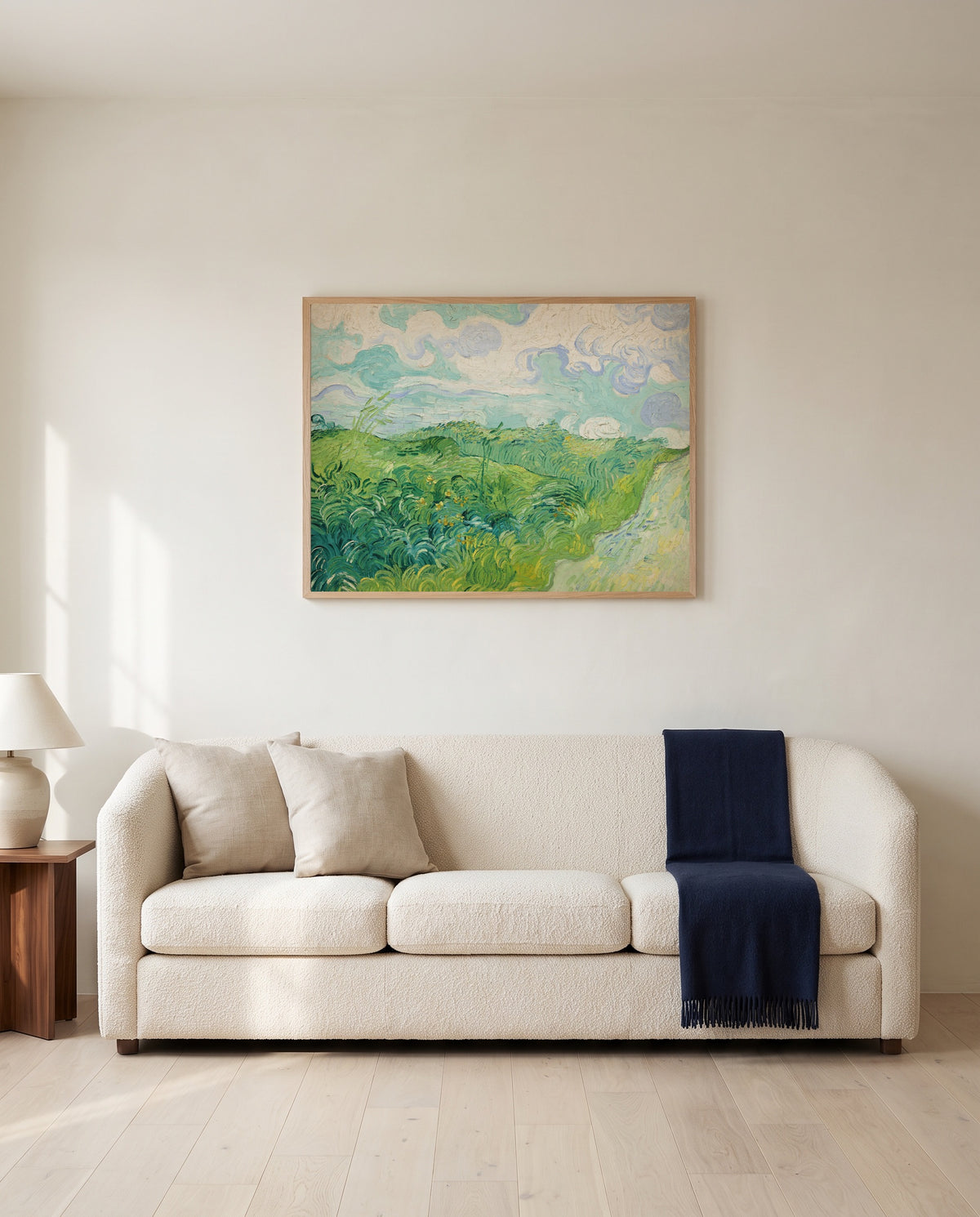 Green Wheat Fields, Auvers by Vincent van Gogh framed in natural oak above a cream sofa in a warm living room