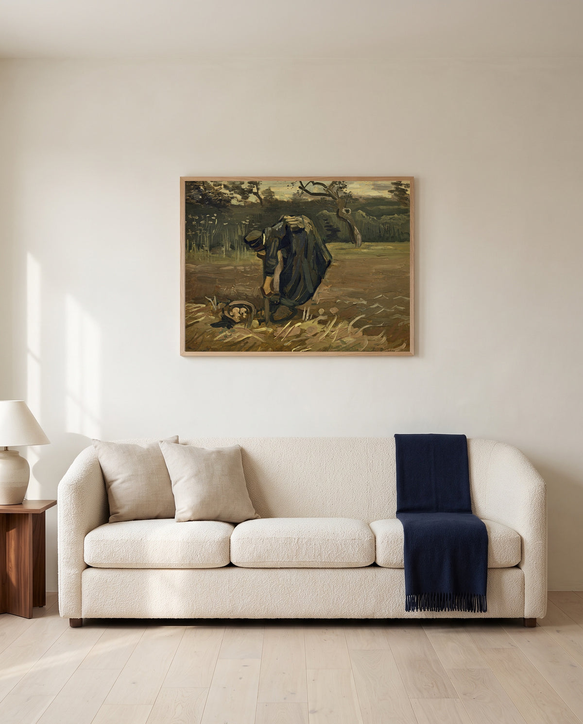 Peasant Woman Digging Up Potatoes by Vincent van Gogh framed in natural oak above a cream sofa in a warm living room